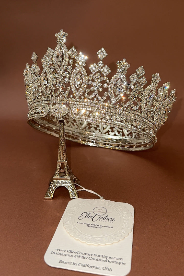 A woman wearing a luxurious Swarovski crystal-embellished bridal crown with intricate details and a full, majestic design.