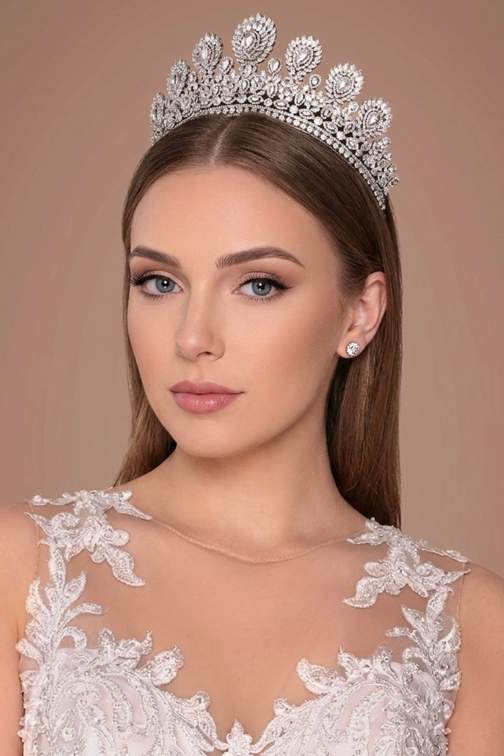 Woman wearing a sparkling tiara and elegant dress against a brown background